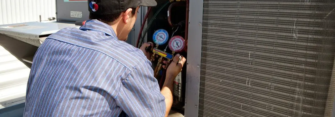 HVAC technician servicing a condenser unit in Hobart