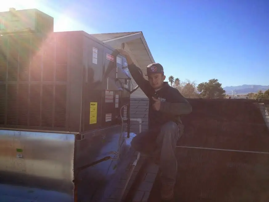 HVAC technician performing Heat Pump Repair on a rooftop unit in Hobart